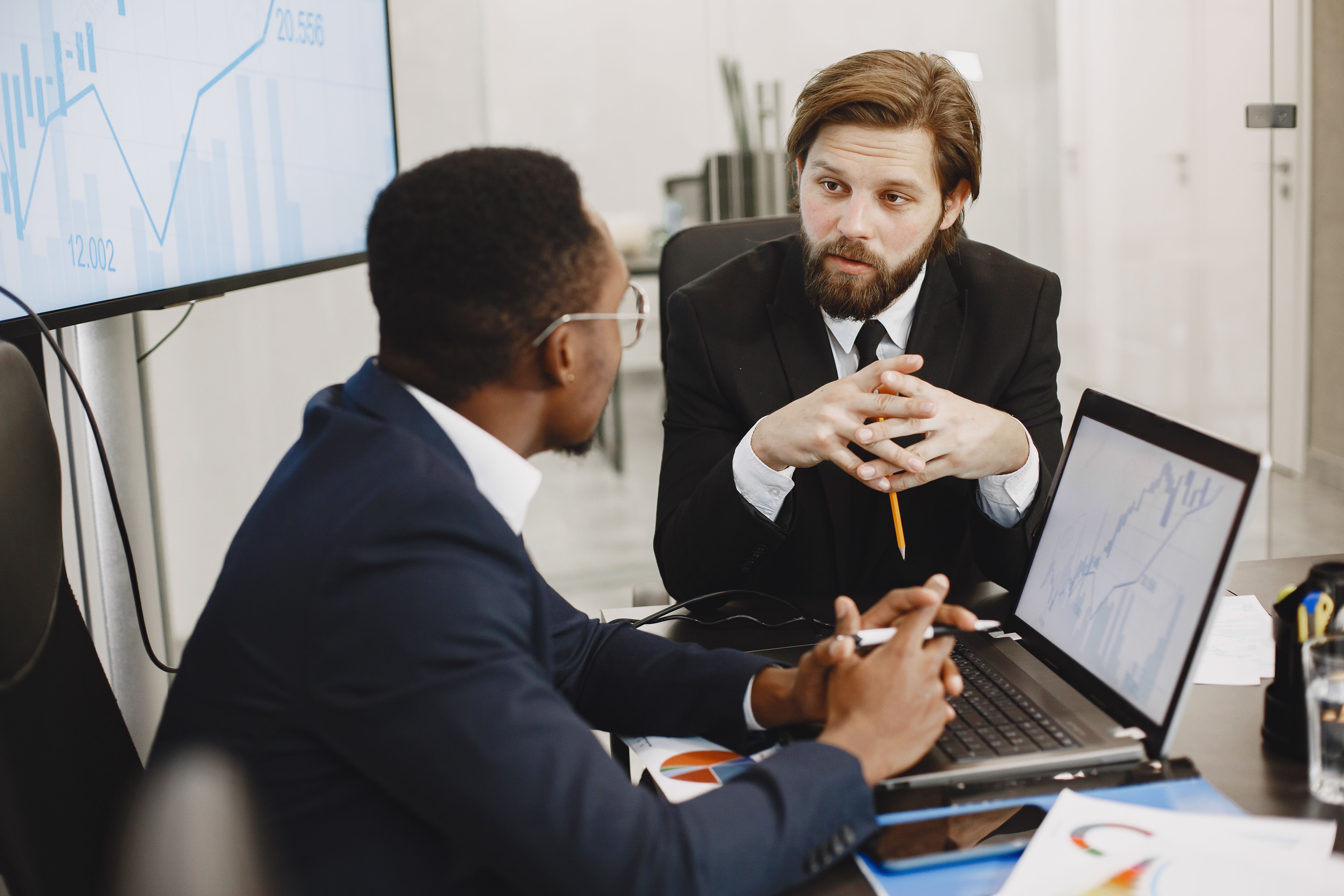 Two consulting professionals reviewing data dashboards during a partner advisory discussion.